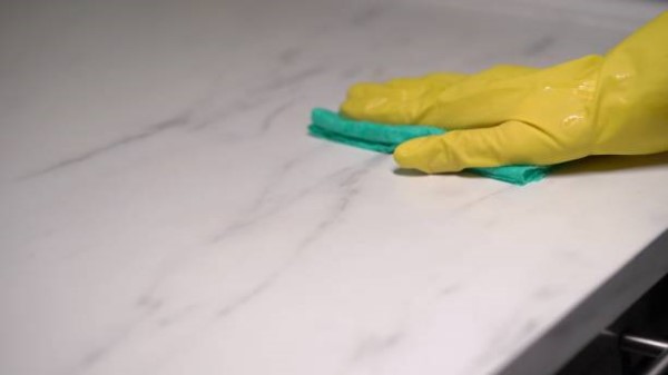 Como pulir mármol; una mano con un guante amarillo y un paño