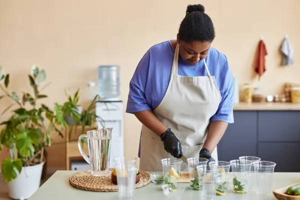 Mujer negra haciendo limonada para la venta en las barras para cocina de un café
